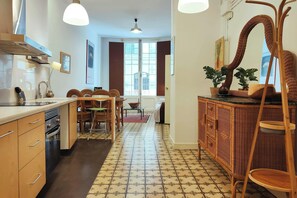 The open floor plan of this apartment creates a sense of spaciousness, with the kitchen seamlessly flowing into the dining and living areas. The  wicker furniture adds warmth and texture, creating a welcoming atmosphere.  This is a great spot to relax aft