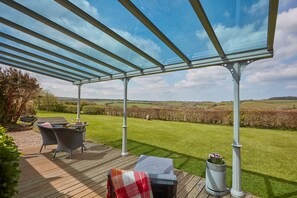 Meadow View, Newquay. Large decked veranda with glazed roof, sun loungers, outdoor furniture and a charcoal barbecue
