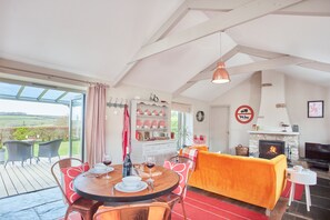 Meadow View, Newquay. Sitting room area with a plush velvet sofa, Smart television, wood burning stove and patio doors