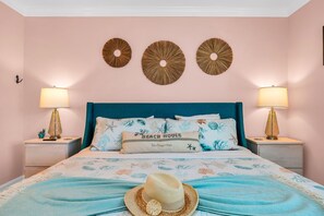 The Primary suite is located adjacent to the kitchen and dining area. It features a coastal-themed king-sized bed, abundant closet space, and an en-suite bathroom boasting a luxurious shower.