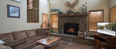 Classic cabin details abound in the striking living area with its tall ceilings, vintage snowshoes and stone, wood-burning fireplace. The space is rounded out with a large sectional, two armchairs, a coffee table and a flat-screen TV.