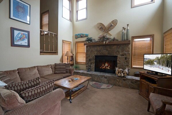 Classic cabin details abound in the striking living area with its tall ceilings, vintage snowshoes and stone, wood-burning fireplace. The space is rounded out with a large sectional, two armchairs, a coffee table and a flat-screen TV.