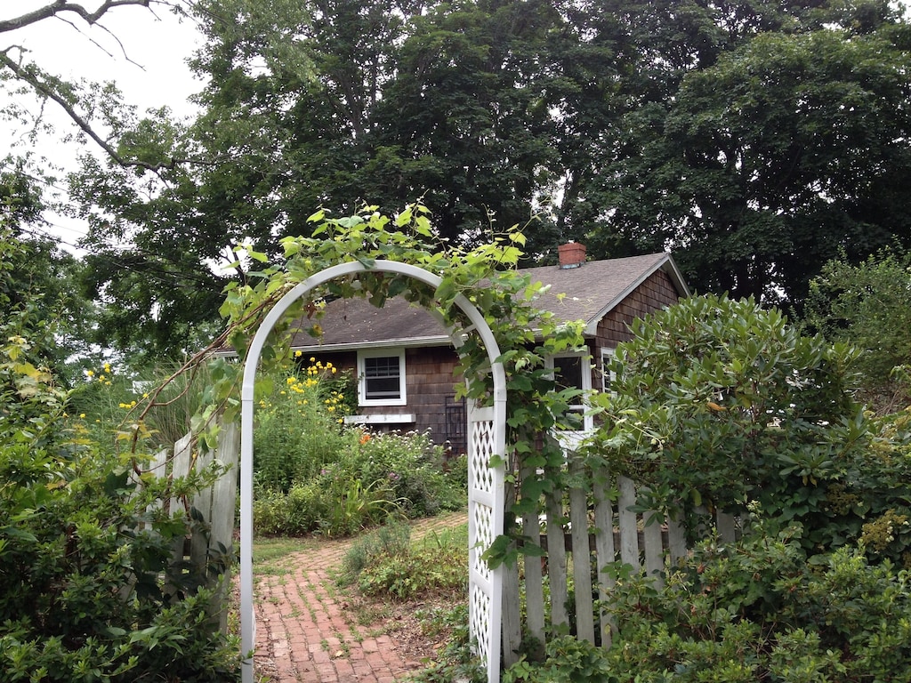 A garden pathway with trellis leads to a Connecticut cottage