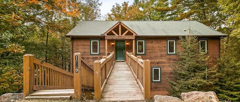 Enter the cabin sanctuary through a charming gateway, where warmth and tranquility welcome you to your haven in the woods.