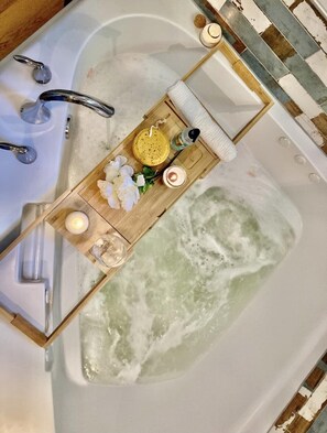 Relax and unwind in the jacuzzi. A wooden tub tray and complimentary bath salts are provided