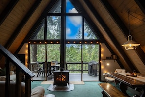 Great room with floor-to-ceiling windows, showcasing sweeping views of the sky and surrounding trees.