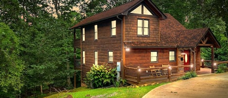 Cabin at sunset, cozy and rustic among the trees with a welcoming circular driveway that promises serenity and seclusion.