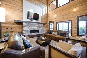 The living room has lounge seating around the stone fireplace.