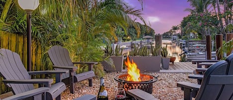 Waterside seating with firepit in the bottom of this tropical yard