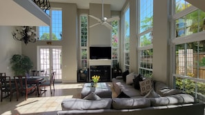 Living room with 65" 4K Samsung TV, wood-burning  Fireplace & Door to backyard.