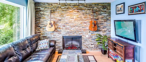 Living room with a couch that turns into a sleeper sofa. Smart TV with YouTube TV for cable, guitars, electric fire place and a great view of the river! Private patio connected to this condo.