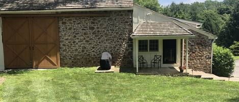 View of barn and entrance with patio chairs and gas grill 