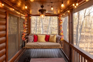 Porch swing in the screened-in porch, beautifully lit by outdoor string lights