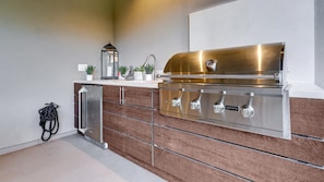 Private outdoor kitchen includes a gas grill, sink, and wine fridge