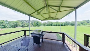 Huge covered patio with view of river, with gas grill & outdoor table & chairs.