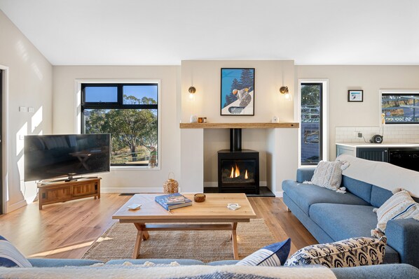beautiful open plan living with wooden floors, pitched roof and gas woodburner