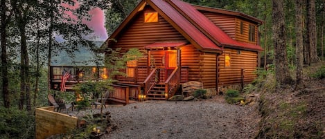 This photo shows the exterior of our cozy cabin nestled in the Blue Ridge Mountains in Georgia. The cabin sits in a scenic location with a stunning view of the mountains and forest in the background. 