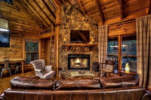 This cozy cabin living room is the perfect retreat for any getaway. A warm and inviting wood burning fireplace is the centerpiece of the room, surrounded by stylish furniture, a soft rug, and rustic decor.