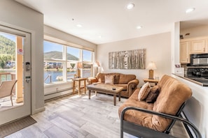 Living area featuring a gas fire place, mounted smart TV, and beautiful views of the lake and mountains out the window.