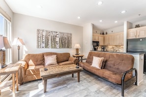 Living area featuring a gas fire place, mounted smart TV, and beautiful views of the lake and mountains out the window.