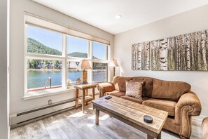 Living area featuring a gas fire place, mounted smart TV, and beautiful views of the lake and mountains out the window.