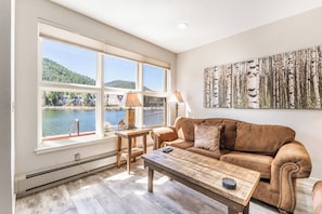 Living area featuring a gas fire place, mounted smart TV, and beautiful views of the lake and mountains out the window.