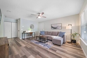 The spacious living room features a large sectional sofa and work desk.