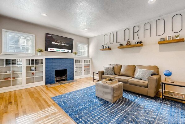 Relax and hangout in the spacious living room that features 2 queen-sized pull-out sofas and a 65 inch 4k Roku Smart TV over a beautiful, decorative brick fireplace.