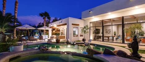 Luxury resort style backyard with heated pool, spa, fire pit, and putting green 