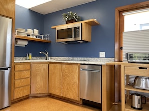 Fully equipped kitchen has fridge, freezer, stovetop, microwave and dishwasher.