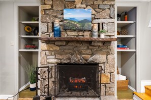 The gorgeous stone fireplace includes an electric fire with flames, heat, or both. Art: "Rhododendron Tree Flowering, Blue Ridge Parkway, North Carolina"