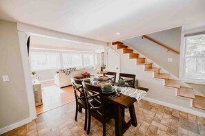Step into the cozy dining area, perfectly situated between the inviting kitchen and the living room. The stairs lead up to the loft, and the large windows flood the space with natural light, offering a warm and airy atmosphere perfect for relaxation.