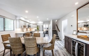 The dining space features a table with seating for six, but also boasts a bar area with a wine fridge for easy serving while you dine. This view shows its convenient location near the kitchen.