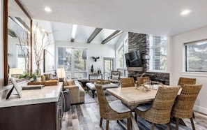 The dining space features a table with seating for six, but also boasts a bar area with a wine fridge for easy serving while you dine. This angle highlights its close proximity to the living area.