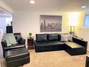 Living room with cozy chair & ottoman, & sofa with pull-out bed