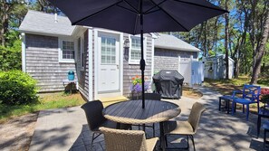 Patio with dining table, gas grill, Adirondack chairs and path to outdoor enclosed shower