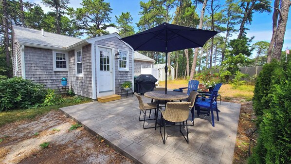 Patio with dining table, gas grill, Adirondack chairs and path to outdoor enclosed shower