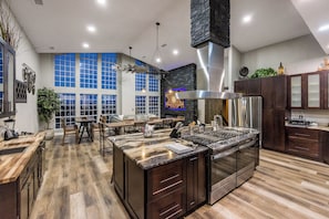 Great room / Kitchen centrally located in the home. 60” stovetop with 8 gas burners, 2 griddles, seating for up to 20 people, 86” Smart TV, 17’ floor to ceiling windows with incredible views of the Prescott Mountains.
