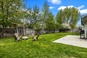 Fenced in backyard with small fire pit.