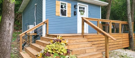 The humble blue tiny house meets you with its wrap around deck.