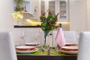 Elegant dining table setup with fresh flowers, wine glasses, and decorative plates.
