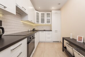 Fully equipped kitchen with white cabinets, modern appliances, and a sleek finish.
