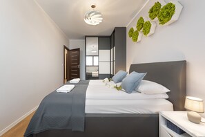Cozy bedroom with a large bed, stylish gray bedding, and wall decorations.
