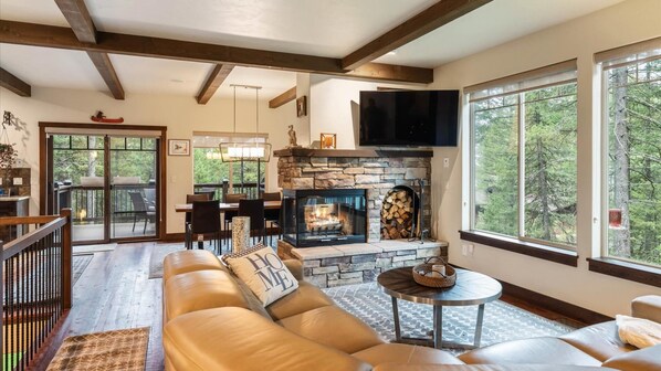 Open concept great room with luxury reclining leather sofa, wood burning fireplace, HDTV with streaming capabilities and alpine views.