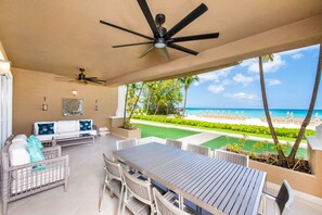 The oceanfront patio comes furnished with an outdoor dining table and plush lounge seating.