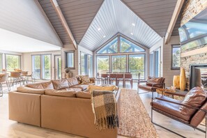 Living area featuring vaulted ceilings, picture frame windows, a gas fire place, and mounted TV.