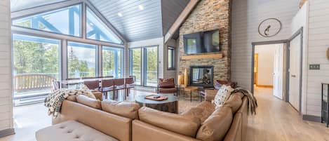 Living area featuring vaulted ceilings, picture frame windows, a gas fire place, and mounted TV.