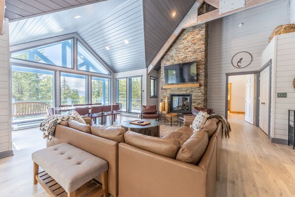 Living area featuring vaulted ceilings, picture frame windows, a gas fire place, and mounted TV.