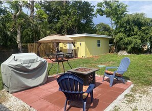 View of backyard BBQ grill, firepit, and cottage with patio