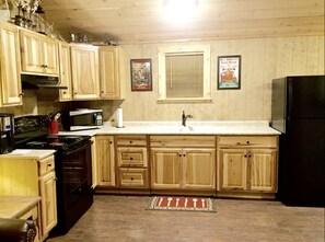 The kitchen is fully stocked with pots, pans, a skillet, cooking utensils & more